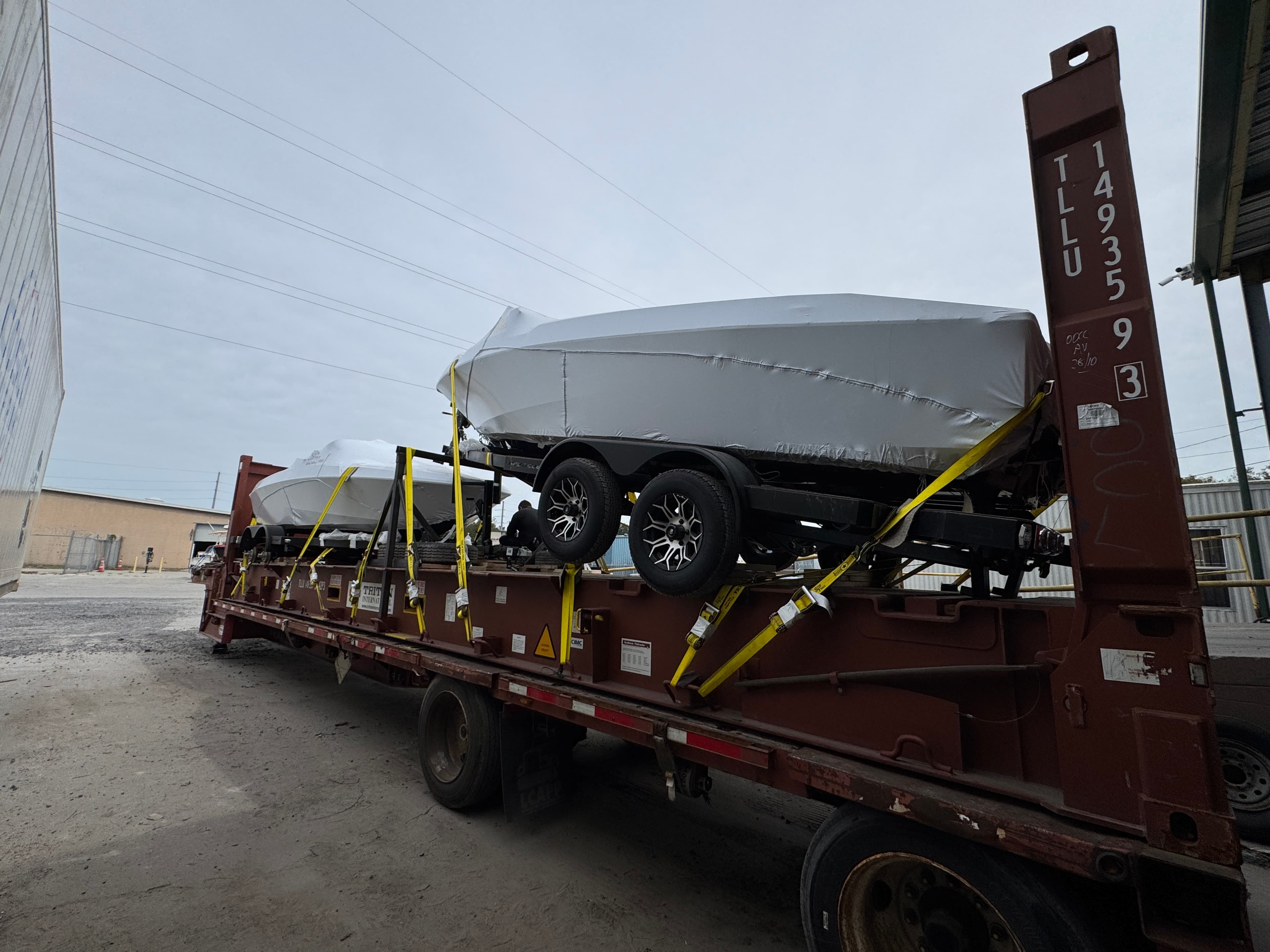 Step deck trailer loaded with boats on a 40-foot flat rack